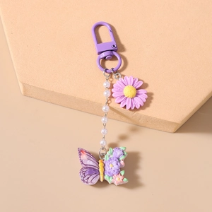Detailansicht von lila Gänseblümchen- und Schmetterlingsanhängern mit Perlenkette