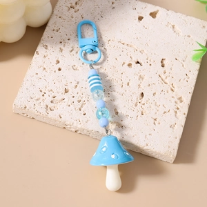 Detail shot of a beaded mushroom keychain with blue lobster clasp on a stone base