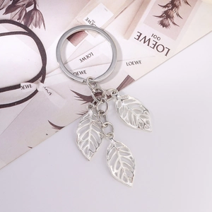 Detailed close-up of a silver leaf keychain with three hollow leaf charms on a magazine
