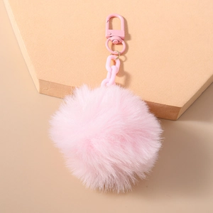 Vue détaillée d'un porte-clés pompon en fausse fourrure rose sur un support chic