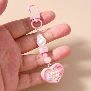 Close-up of pink heart keychain with Forever Love inscription and pearl beads