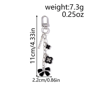 Detail of keychain with clover charms, black bow, pearls, and dimensions shown