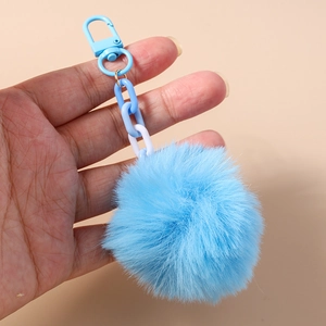 Détail d'un porte-clés à pompon bleu ciel en fausse fourrure douce avec un crochet assorti