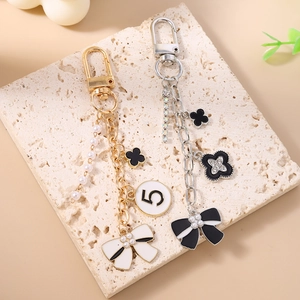 Elegant gold and silver keychains with pearls, black clover, and ribbon bow charms