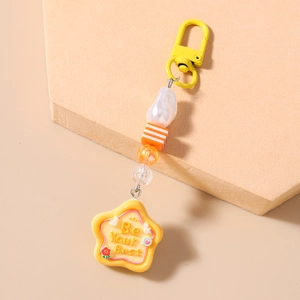 Detail of warm yellow beaded keychain with striped cubes pearls and Be Your Best star charm