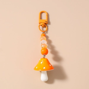 Detail of orange mushroom keychain with white polka dots and striped beads charm