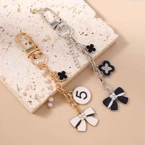 Elegant keychain with bow, pearl tassel, and clover charms on a stone background