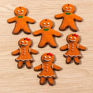 Close-up of wooden gingerbread man pendants with festive red and green ribbon details