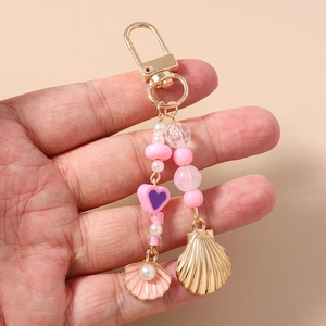 Detail of beaded keychain with pink enamel shell, golden starfish, and heart charms