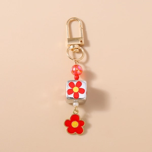 Dettaglio di un portachiavi con fiore rosso con chiusura dorata e ciondolo smiley