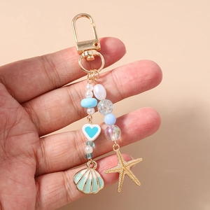 Detail of ocean-themed keychain with starfish, shell, pearl beads, and blue heart charm