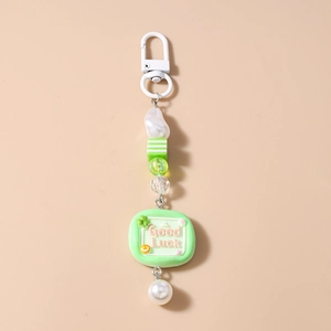 Detail of green striped beads and Good Luck charm on a pearl keychain accessory