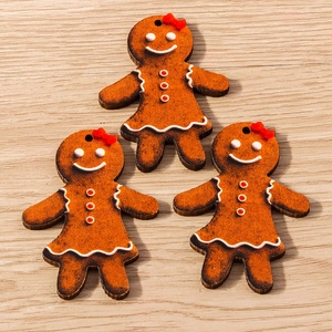 Three gingerbread man wooden pendants with red bows on a light wood grain background