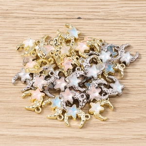 Macro detail of star and moon charms with iridescent opal inlay and golden metallic finish