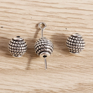 Macro detail of antique silver pumpkin lantern spacer beads with granulated texture
