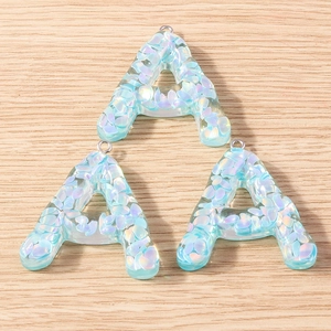 Macro view of light blue resin letter A charms with shimmering iridescent sequins and metal rings