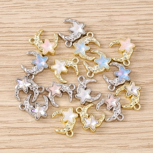 Macro detail of star and moon charms with opal-like stones on a light wood background