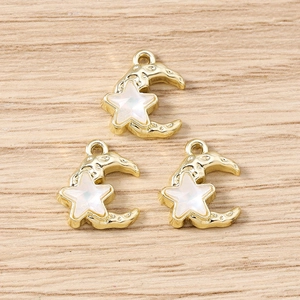 Macro shot of three star and moon charms with opal inlay on light wooden surface