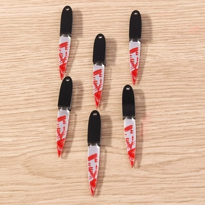 Macro shot of miniature acrylic horror cleaver charms with realistic red blood splatters