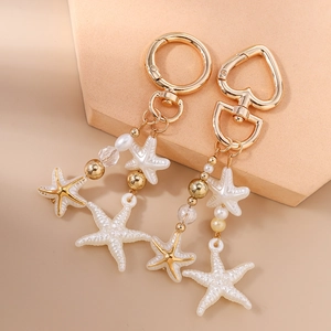 Detailed macro of gold-plated starfish charms with pearls and beads on display