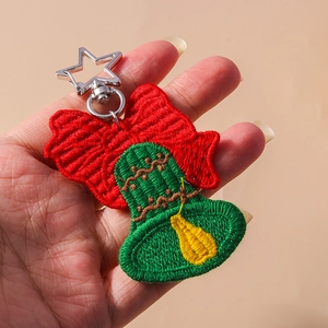 Christmas bell keychain with red bow and star-shaped metal clasp held in hand