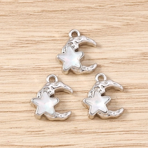 Detailed view of silver star and moon charms with moon crater texture and opal inlay