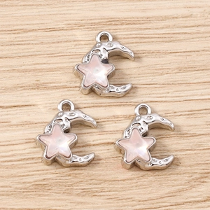 Macro detail of crescent moon and star charms with pink shell texture and silver base