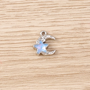 Macro detail of crescent moon and star charm with iridescent gems and metallic texture
