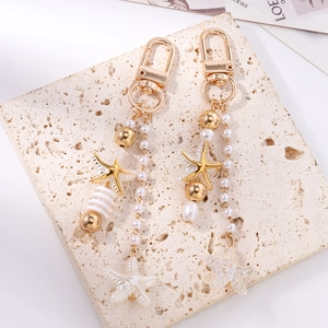 Detailed shot of starfish charms with white pearls and gold beads on a stone surface