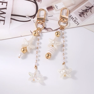 Detail view of starfish charms with white striped beads and long pearl chains on gold clasps