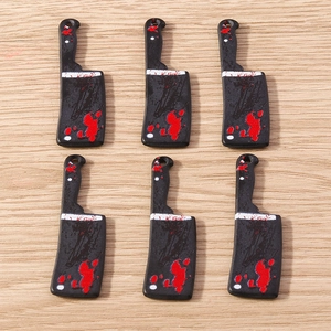 Detailed view of mini Halloween meat cleaver charms with red blood splatter patterns