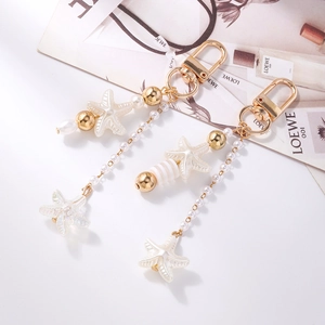Detail view of pearl starfish keychains with gold clasps on a stylish fashion magazine