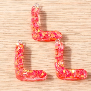 Close-up of letter L resin charm with pink glitter for DIY jewelry and necklaces