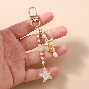 Detail of starfish and pearl keychain with golden lobster clasp held in hand