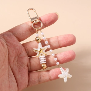 Handheld view showing golden starfish and pearl keychain bag charm detail