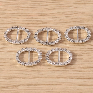 Detail of five silver oval rhinestone slide buckles for DIY jewelry on wooden background