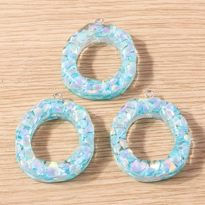 Close-up of three iridescent blue petal resin pendants with silver metal hooks for DIY