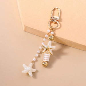 Detail of nautical keychain with starfish charms, pearls, and golden metal clasp