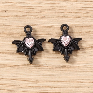 Macro view of gothic bat-wing heart charms with pink crystal and black alloy finish