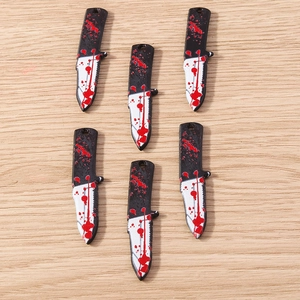 Detailed close-up of spooky miniature knives with blood splatter for DIY Halloween jewelry