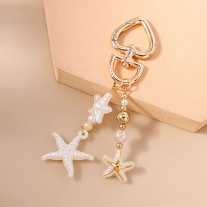 Detail of starfish charms and pearls on a gold heart-shaped lobster clasp keychain