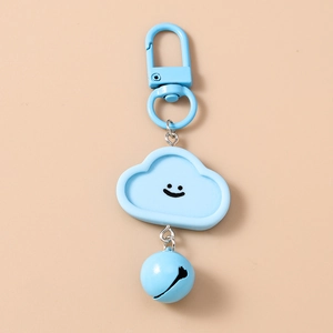Gros plan d'un porte-clés nuage bleu clair avec un visage souriant et une clochette