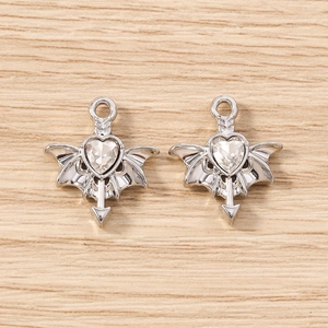 Macro shot of silver winged heart charms with clear cubic zirconia on wooden surface