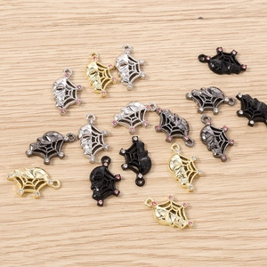 Close-up of gothic skull and spider web alloy charms with rhinestones on wood