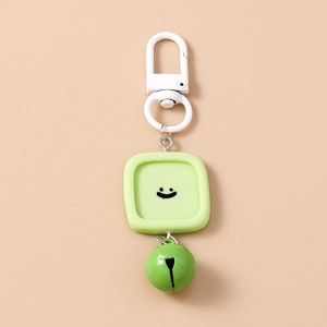 Détail d'un porte-clés avec cloche en métal vert et pendentif carré sourire en silicone