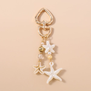 Detail of starfish charms with white pearls and gold beads on a heart keychain
