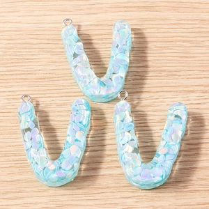 Close-up of translucent blue U-letter resin charms with colorful glitter and silver loops