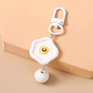 Détail du porte-clés œuf au plat créatif avec clochette blanche et pendentif sourire
