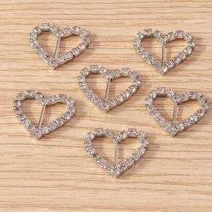 Macro view of 6-piece silver heart-shaped rhinestone buckles on light wood background