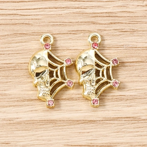 Detailed view of two gold skeleton spider web charms with pink rhinestones for DIY jewelry